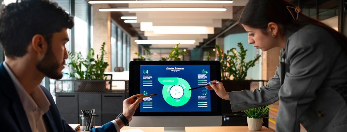 Two professionals in an open-plan office collaborate and point at a desktop monitor showing a detailed infographic about a new AI-powered QA automation process flow, highlighting test cycle and bug reduction results.