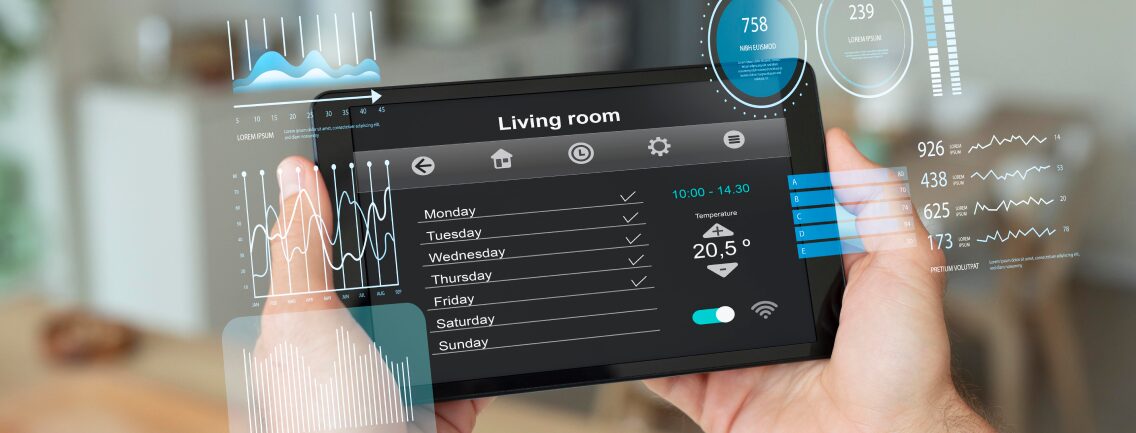 A multi-ethnic team of engineers on a factory floor reviews transparent holographic data visualizations and dashboards on a laptop, demonstrating the predictive monitoring required for Scaling IoT infrastructure.